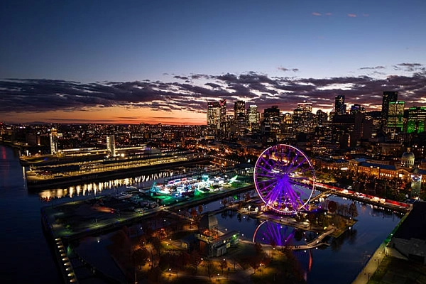 Dusk skyline view of Montreal featuring the illuminated La Grande Roue de Montréal at the Old Port of Montreal along the waterfront.