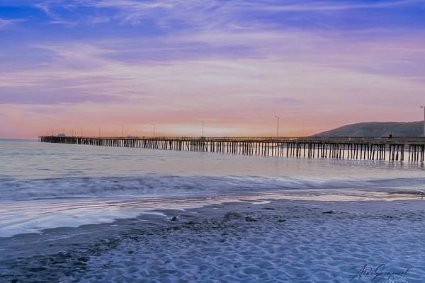 Avila Beach Pier at sunset with ocean waves and colorful sky in California
