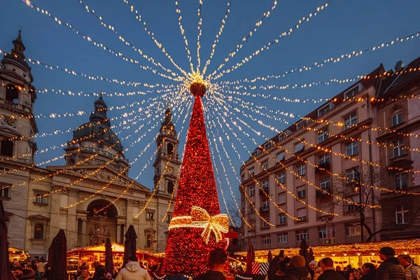 Christmas market in Europe with a large decorated Christmas tree, festive lights, and holiday stalls in a historic city square