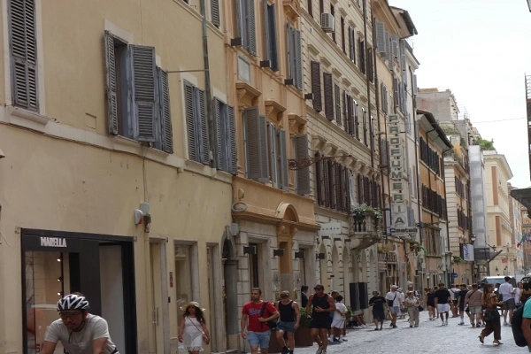 Historic European street with pedestrians walking past centuries-old buildings during a guided walking tour