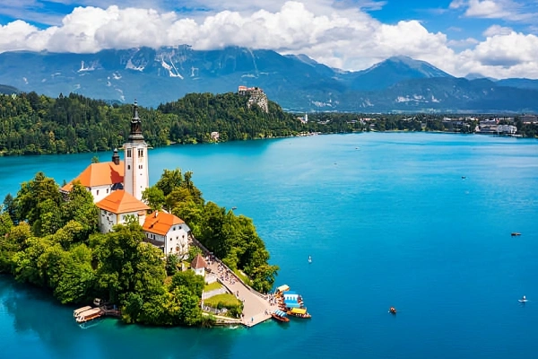 Aerial view of Lake Bled Island with Assumption of Mary Church, Bled Castle on cliff, and Julian Alps in background, Slovenia