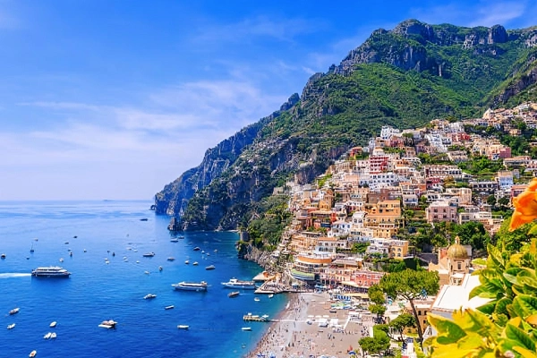 A panoramic view of Positano’s colorful cliffside buildings overlooking the blue Tyrrhenian Sea and the iconic dome of Santa Maria Assunta Church.