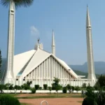 Faisal Mosque Islamabad with Margalla Hills backdrop, lush greenery and clear blue sky in Pakistan capital city