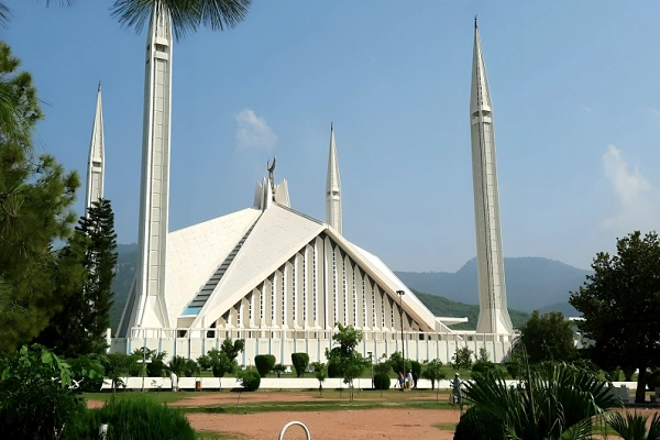 Faisal Mosque Islamabad with Margalla Hills backdrop, lush greenery and clear blue sky in Pakistan capital city