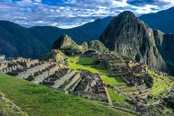 Machu Picchu ruins in the Andes Mountains, Peru with green terraces and dramatic clouds