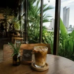 Coffee served inside a modern Bangkok cafe with tropical greenery and city skyline views in Thailand