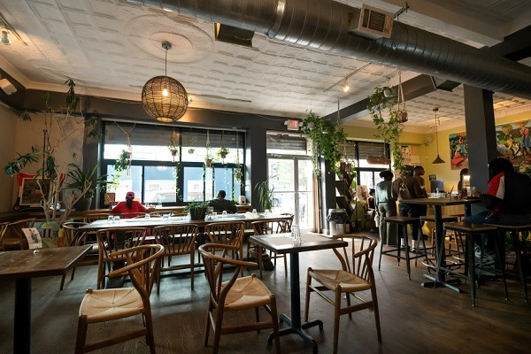 Cozy modern cafe interior in New York City with wooden seating, natural light, and people enjoying coffee