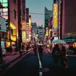 Tokyo street at night with neon signs and pedestrians walking during first-time travel in Japan