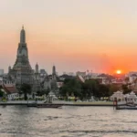 Bangkok skyline and Wat Arun temple along the Chao Phraya River at sunset, Thailand