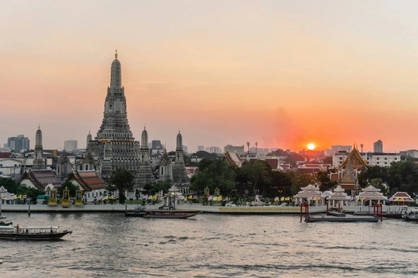 Bangkok skyline and Wat Arun temple along the Chao Phraya River at sunset, Thailand